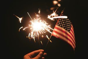time lapse photography of sparkler and U.S.A flag