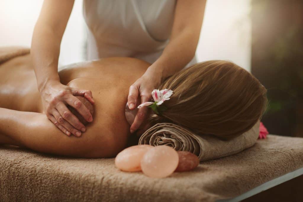 Mature woman enjoy Back massage with Himalayan salt stones in beauty salon